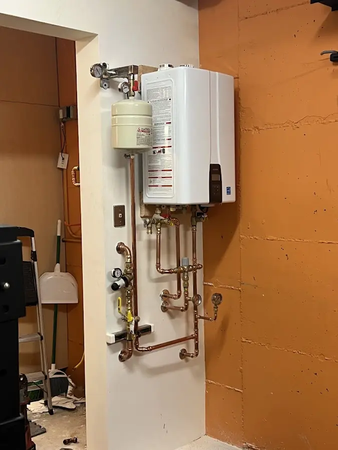 Plumbing technician inspecting water heater connections in Bedford